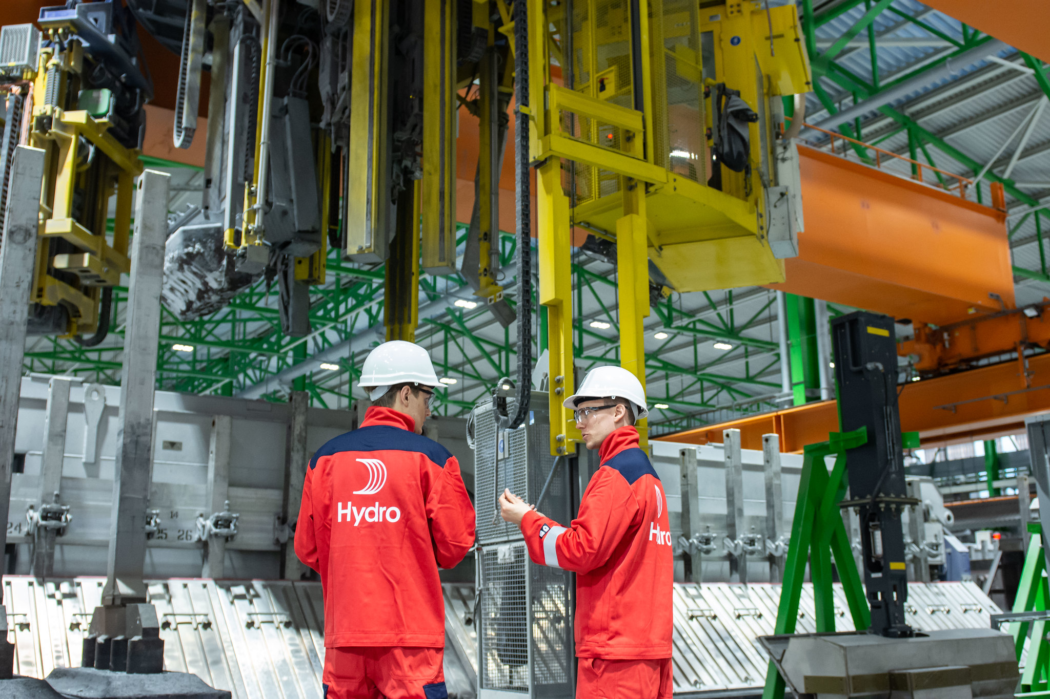 2 Men in Norsk Hydro Branded Uniform inside of a manufacturing plant